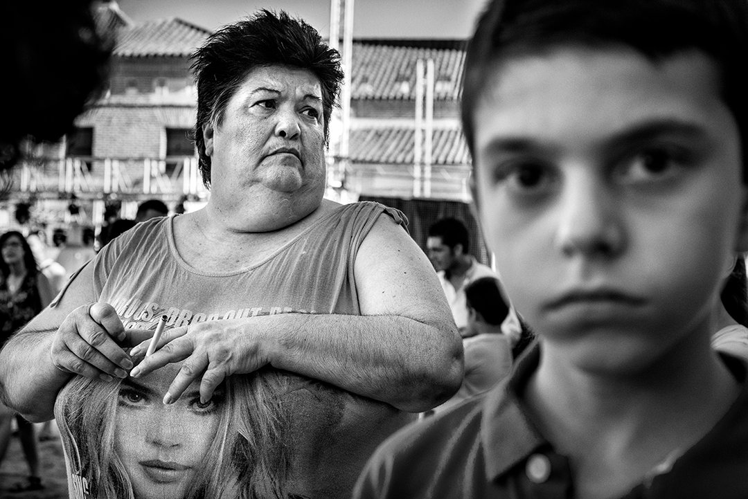 A child in the foreground and a woman behind him on a street.